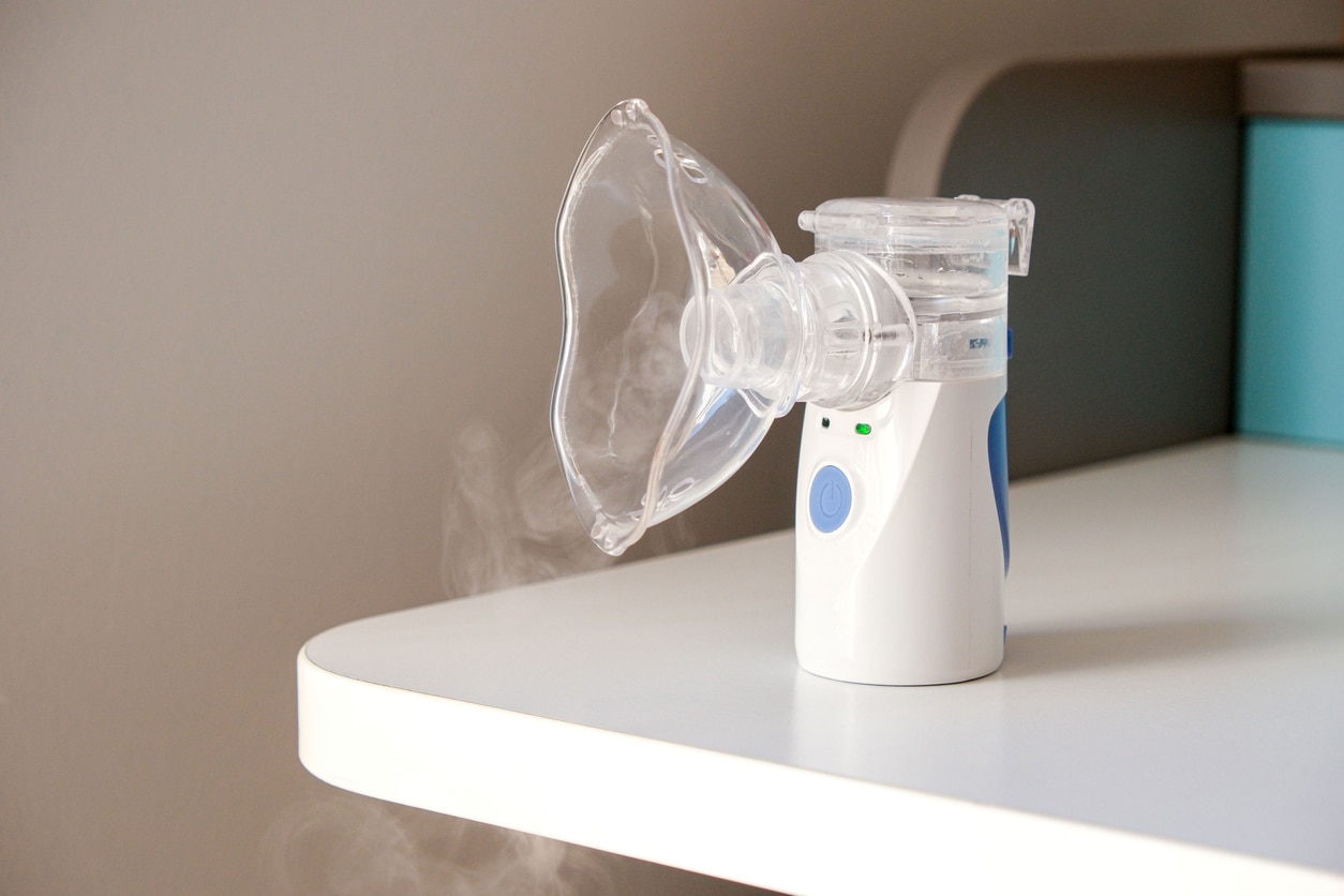 inhalator parowy do zatok w domu mężczyzna trzymający twarz nad dyszą elektrycznego inhalatora parowego