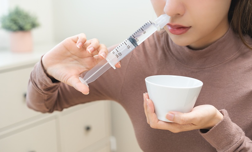przygotowanie soli fizjologicznej do inhalacji mężczyzna trzymający przezroczysty kubek z solą fizjologiczną i kroplomierzem