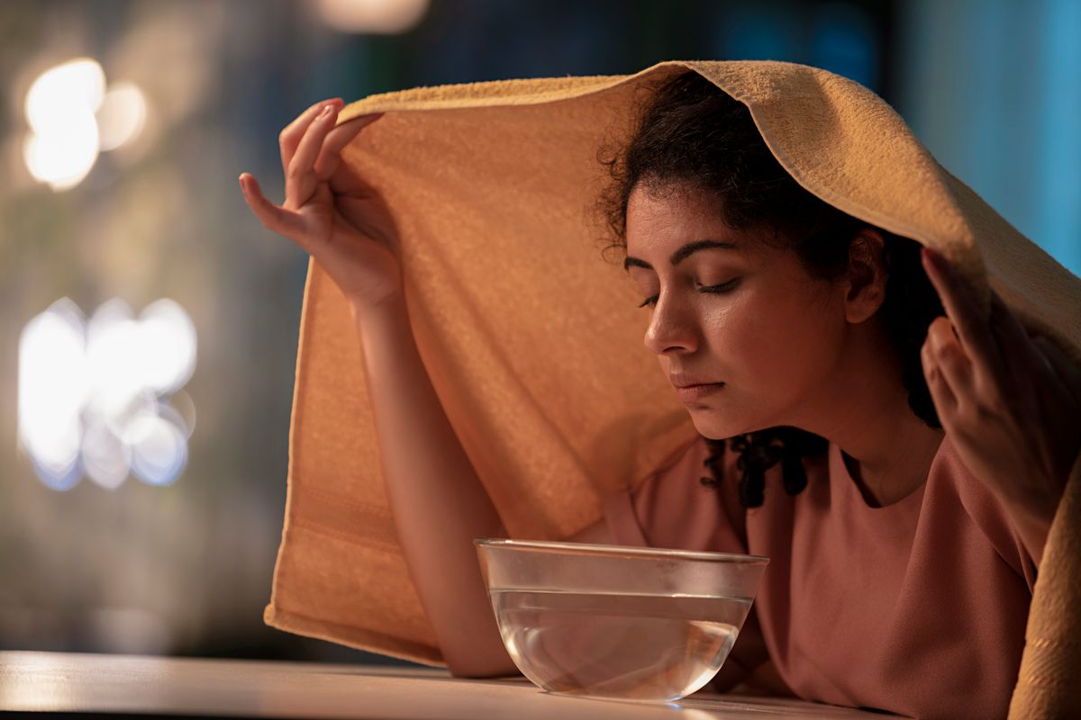 starszy mężczyzna leżący z inhalatorem parowym pod nosem w łóżku